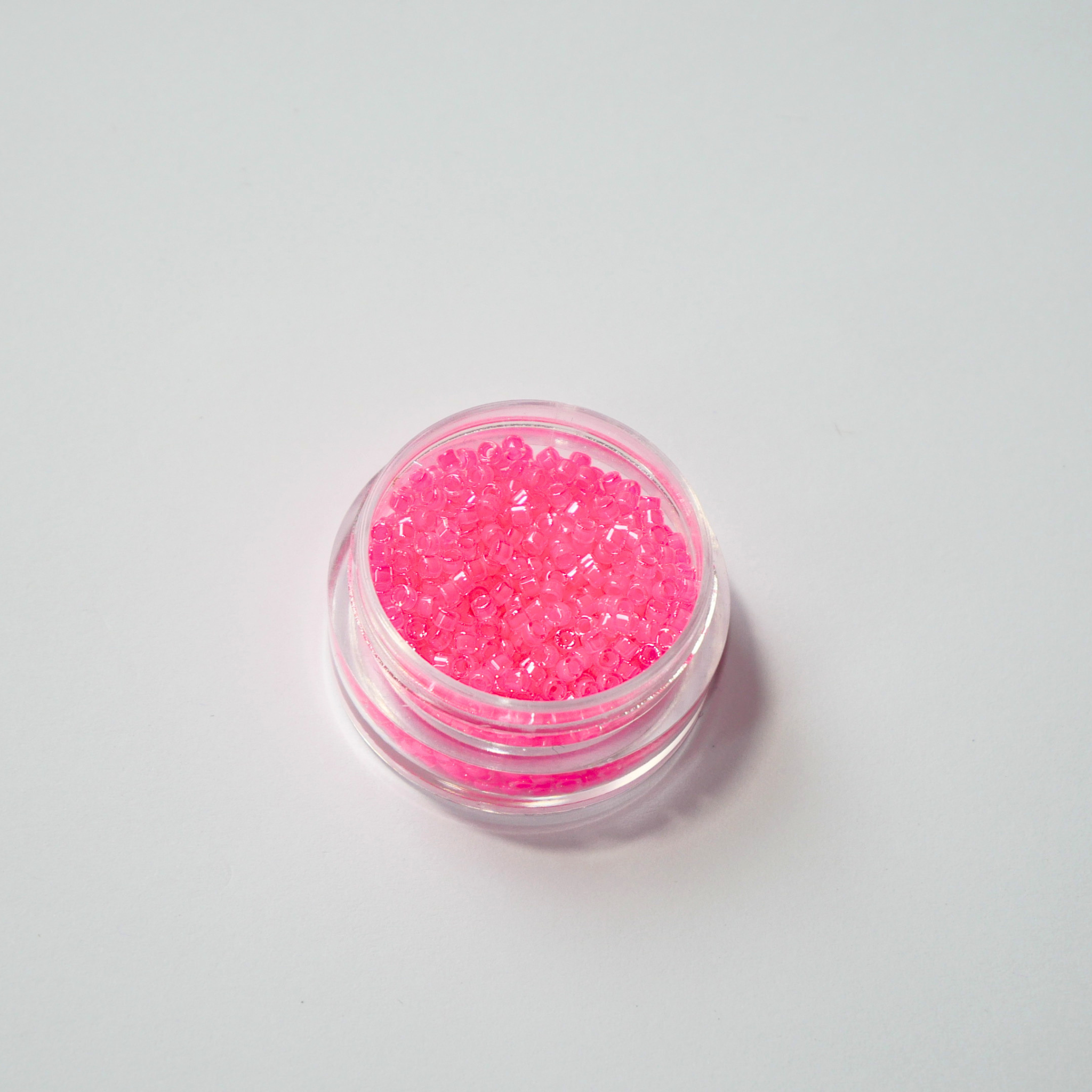 Miyuki Delica 11/0 koodiga DB-2035. Detailne lähivõte neoonsetest helendavatest maasikapunastest (Luminous Wild Strawberry) silindrilistest helmestest.