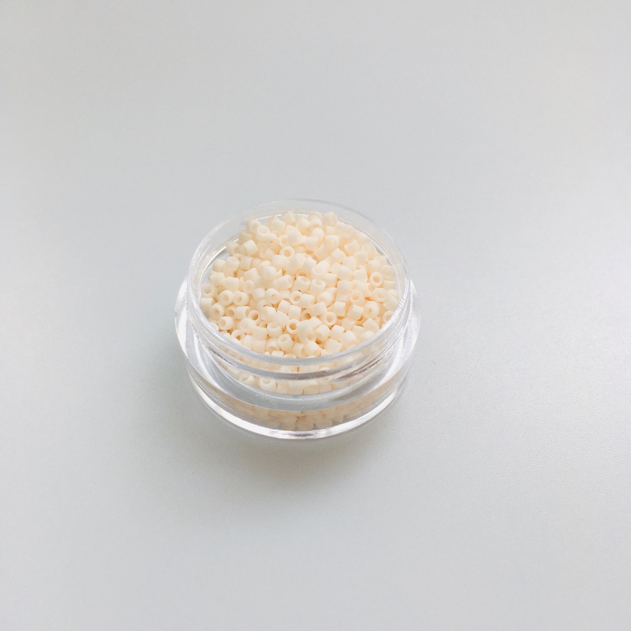 Miyuki Delica 11/0 DB-1510 Opaque Bisque White Mat silindrilised seemnehelmed. Lähivõte näitab sametist matt kreemjasvalget tooni, mis sobib hästi vintage-stiili.