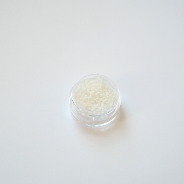 Miyuki Rocailles 15/0 koodiga 402. Detailne lähivõte väikestest puhastest läbipaistmatutest valgetest seemnehelmestest.
